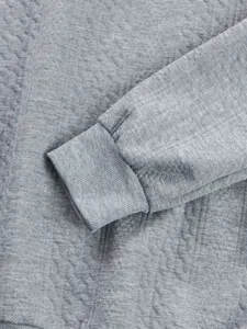 Close-up of the ribbed cuff and textured jacquard fabric of a gray men's sweatshirt