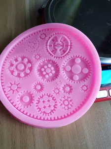 Vista dettagliata dello stampo in silicone rosa con varie forme di ingranaggi per fondente