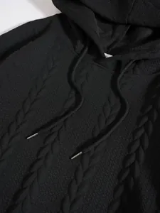 Détail d'un sweat à capuche noir pour homme avec motif texturé en maille torsadée