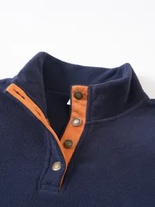 Close-up of navy fleece pullover with contrast orange placket and metal snap buttons