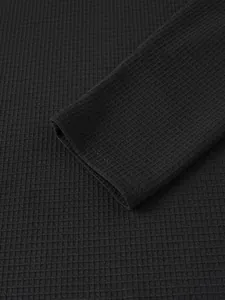 Detailansicht der schwarzen Waffelstrickstruktur und der Ärmelbündchen eines Henley-Hemdes