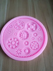 Dettaglio di uno stampo in silicone rosa con intricati motivi di orologeria e ingranaggi per dolci