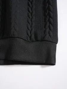 Gros plan sur le tissu jacquard noir et l'ourlet côtelé d'un sweat-shirt homme.