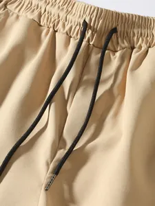 Detail shot of elastic waistband and black drawstring on men's khaki cargo pants.