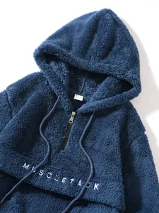 Detailed macro view of blue fuzzy fleece hoodie with MUSCLE TACK embroidery and half zipper
