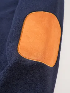 Close-up of orange suede-like elbow patch on navy blue fleece sweatshirt detail