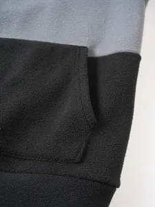 Detail shot of soft black and grey fleece fabric on a men's color-blocked hoodie.