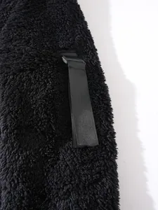 Nahaufnahme von schwarzem flauschigem Fleece-Material mit einem robusten Nylonband