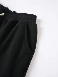 Gros plan d'un pantalon de jogging en polaire noire montrant la taille élastique
