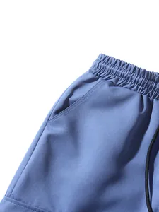 Detailed view of elastic drawstring waistband and side pocket on blue casual pants