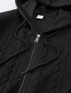 Close-up detail of jacquard texture and metal zipper on men's black zip-up hoodie