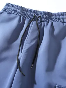 Close-up of elastic waistband and drawstring on blue cargo joggers.