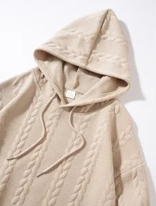 Détail en gros plan d'un sweat à capuche jacquard beige pour homme avec texture torsadée.