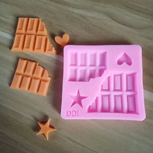 Detalle de un molde de silicona rosa con formas de corazón, estrella y tableta de chocolate.
