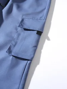Close-up detail of a large side pocket on blue cotton cargo pants with drawstring waist