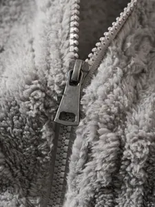 Macro-detail van een duurzame metalen rits op een zachte grijze pluche fleece jas