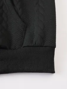 Detailed macro view of black jacquard textured fabric and ribbed hem for men's hoodie