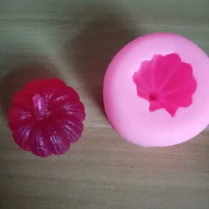Gedetailleerd overzicht van de roze siliconen pompoenvorm en het rode eindproduct.