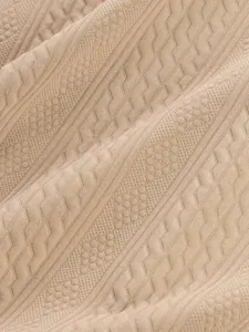 Macro detail of beige jacquard knit fabric showing intricate geometric textures