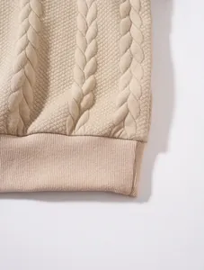 Gros plan sur la maille torsadée beige et l'ourlet côtelé d'un sweat à capuche