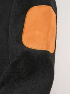 Close-up of black fleece sweatshirt sleeve featuring a contrast orange faux suede elbow patch.