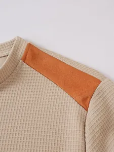 Detailaufnahme der Waffelstrickstruktur mit orangefarbenem Schulteraufnäher.