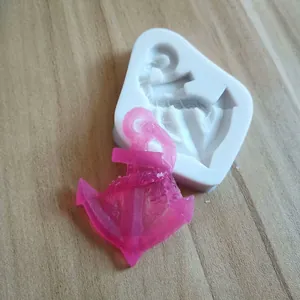 Close-up of anchor shaped silicone mold with a pink resin cast on wooden background
