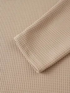 Detail der beigen Waffelstrick-Textur und der genähten Manschette an einem Herren-Henley-Shirt