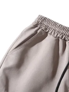 Close-up of elastic waistband and pocket detail on light khaki cargo jogger pants