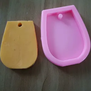Detailed view of pink wine glass shape silicone mold and yellow molded resin keychain tag
