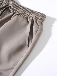 Detailed view of khaki jogger pants featuring an elastic waistband and black drawstring