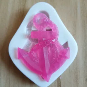 Detail view of white silicone mold with a pink resin anchor shape on wood surface