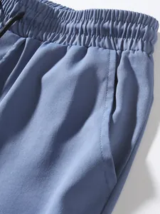 Macro detail of men's blue cargo pants showing elastic waistband and pocket fabric