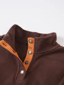 Detail view of brown fleece sweatshirt with stand-up collar and orange button placket