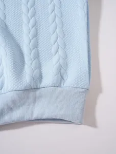 Gros plan détaillé du tissu jacquard bleu clair et de l'ourlet côtelé d'un sweat homme