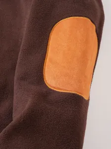 Close-up detail of a contrasting orange elbow patch on a dark brown fleece sweatshirt