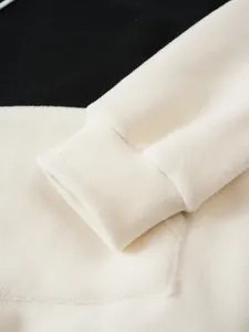 Detailed macro shot of white polar fleece cuff and pocket on a men's color-block hoodie