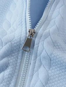 Detailed macro shot of premium silver zipper and jacquard fabric texture on blue hoodie