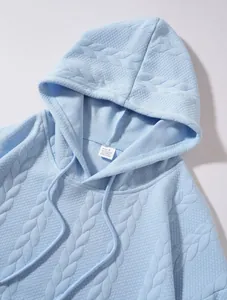 Détail d'un sweat-shirt à capuche jacquard bleu clair avec motif tressé texturé
