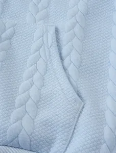 Detailed macro view of light blue jacquard fabric with cable knit and diamond patterns