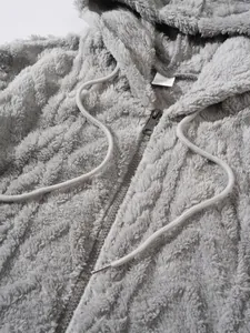 Detailopname van grijze harige hoodie met rits die de zachte pluche textuur laat zien.