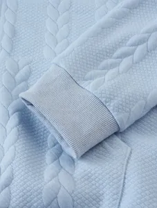 Close-up of light blue jacquard hoodie showing ribbed cuff and fabric texture