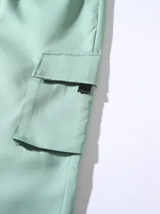 Close-up view of pocket detail on light green cargo joggers with cotton twill texture