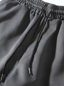 Close-up detail of grey cargo pants showing elastic waistband and metal-tipped drawstring.