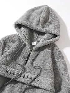 Macro view of a soft grey sherpa fleece hoodie showing embroidered MUSCLE TACK text