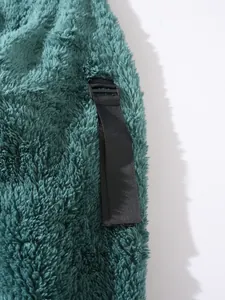 Detailansicht von grünem Fleece-Stoff mit einem verstellbaren schwarzen Riemen.