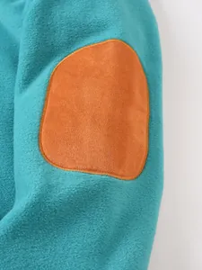 Close-up detail of premium orange suede elbow patch on a teal fleece sweatshirt sleeve.