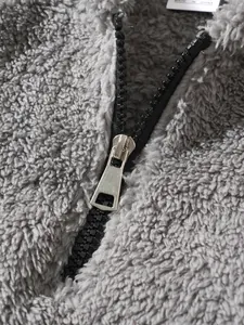 Close-up of high-quality grey sherpa fleece fabric and durable metal zipper detail