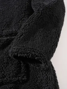 Close-up of black plush sweatshirt fabric showing soft fleece texture and cuff detail.