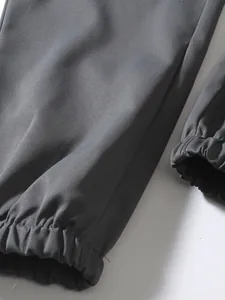 Detail shot of the elasticated cuff on dark gray men's cargo pants, high quality fabric.